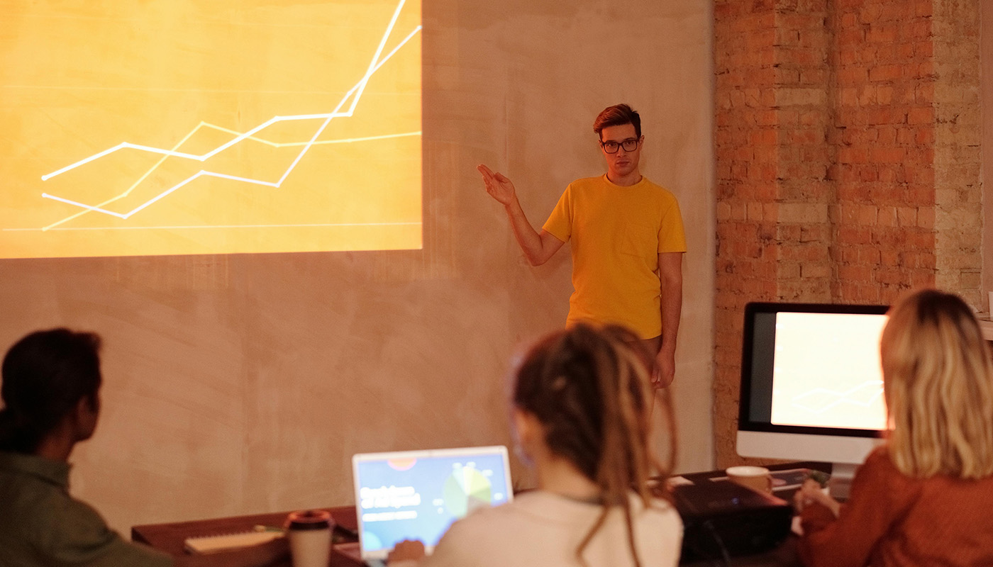Man in yellow presenting data to the team.
