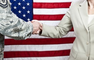 "A handshake between a military person and a civilian against the backdrop of an American flag."