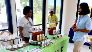 Two people interacting at a booth with a variety of products on display.