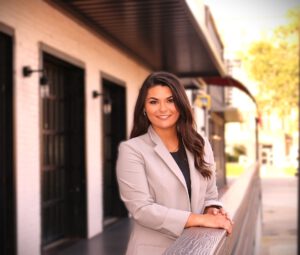 A woman standing on a porch in front of a residence.